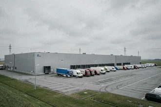 Vue extérieure du site hub logistique d'Harnes dans le Pas-de-Calais, avec quais de chargement et camions de livraison